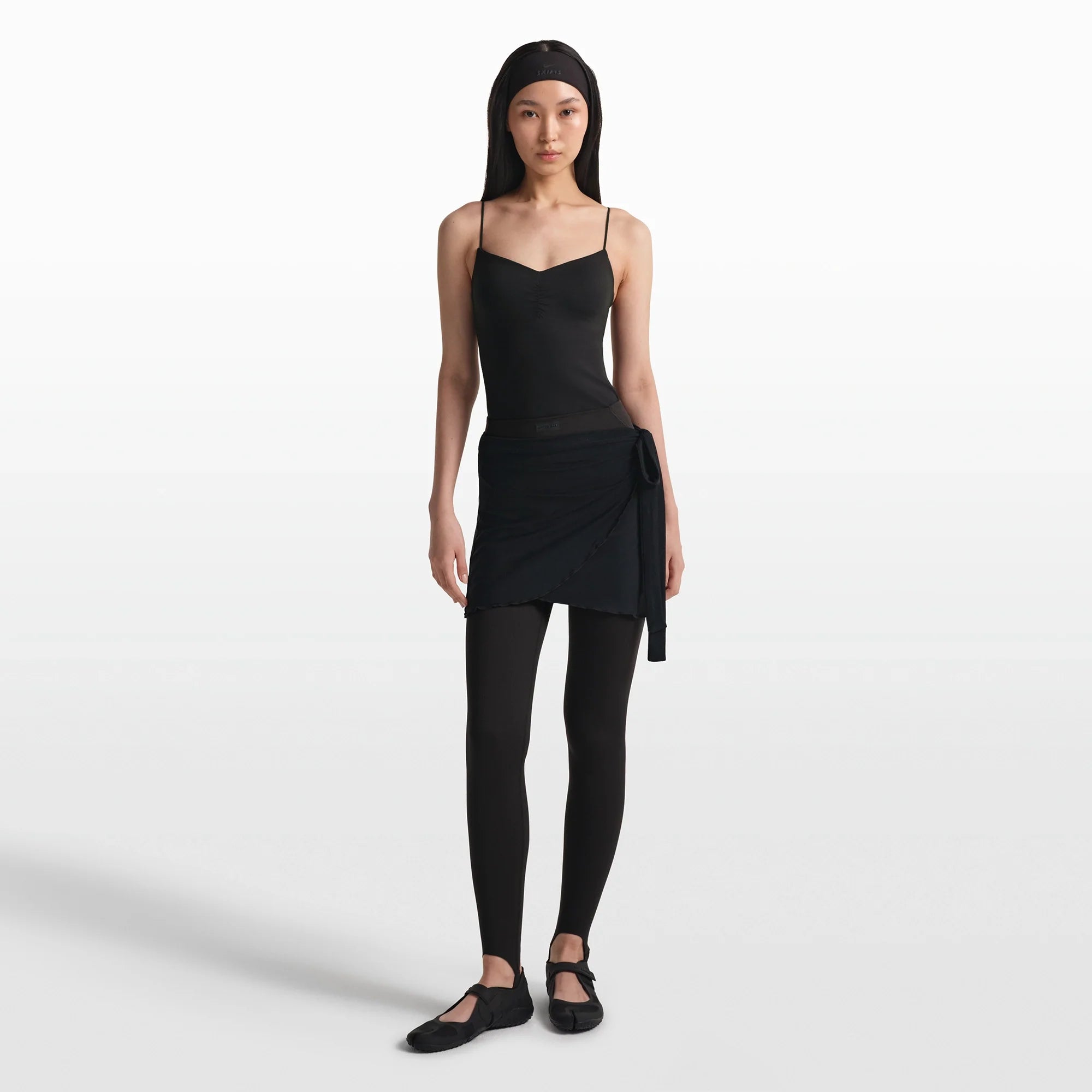 NikeSKIMS MATTE V-LINE STIRRUP LEGGING | OBSIDIAN ON A MODEL FRONT VIEW @ | FOCUS: 0.0, 1.0, 0.9
