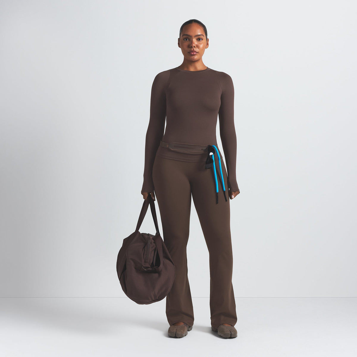 NikeSKIMS MATTE SLIM FLARE LEGGING | DARK SEPIA ON A MODEL FRONT VIEW @ | FOCUS: 0.9, 0.1, 0.7