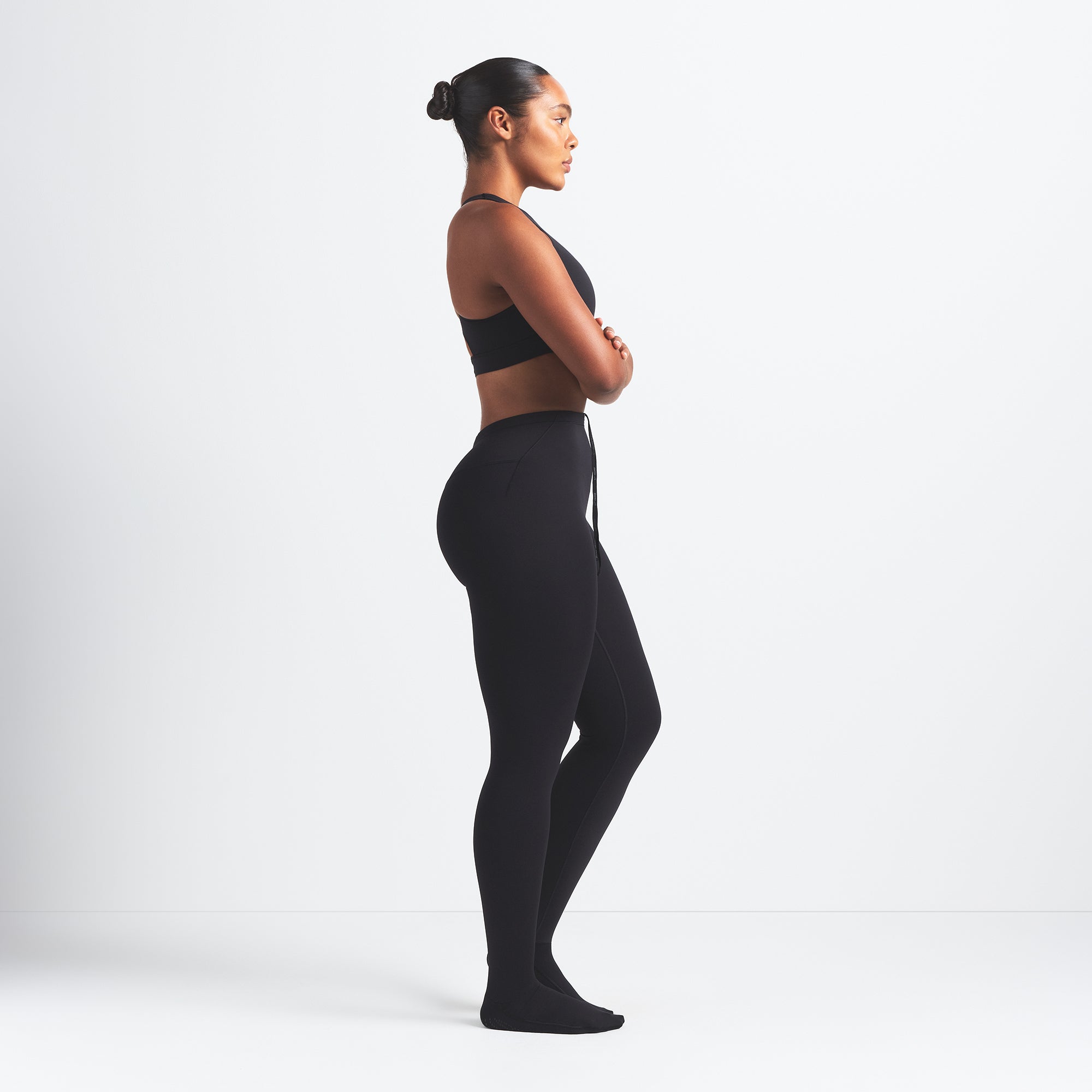 NikeSKIMS MATTE FOOTSIE GRIP LEGGING | OBSIDIAN ON A MODEL SIDE VIEW